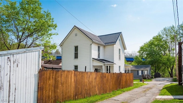 view of side of home with fence and metal roof