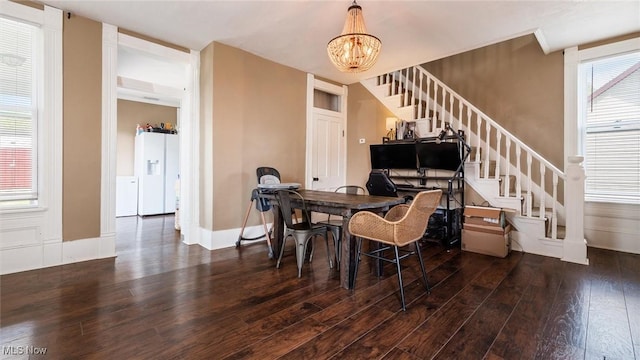 dining space featuring baseboards, an inviting chandelier, wood finished floors, and stairway