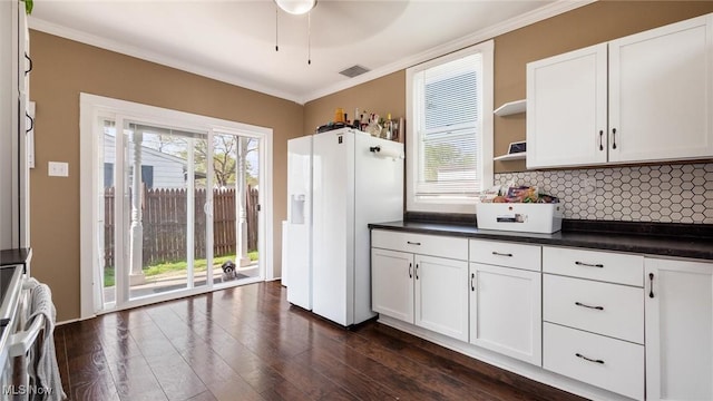 kitchen featuring dark countertops, backsplash, range, and white fridge with ice dispenser