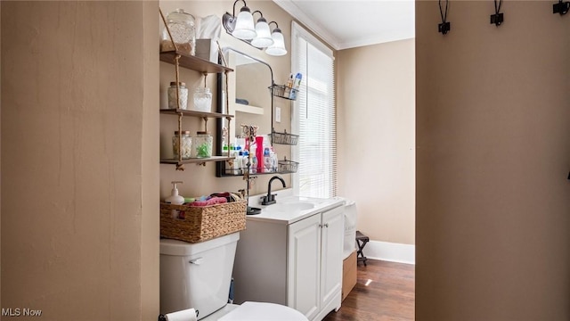 bathroom featuring vanity, ornamental molding, wood finished floors, toilet, and baseboards
