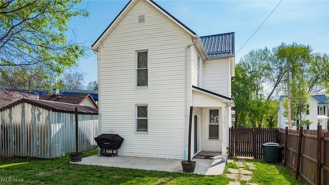rear view of property featuring a yard, fence, and metal roof