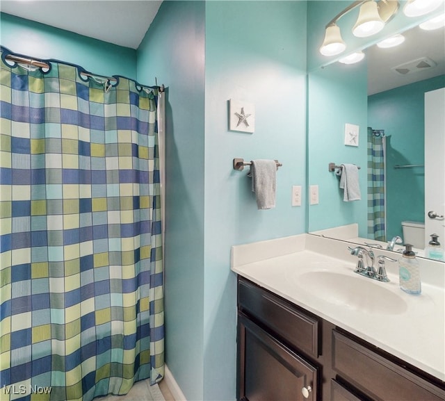bathroom with vanity, toilet, curtained shower, and visible vents