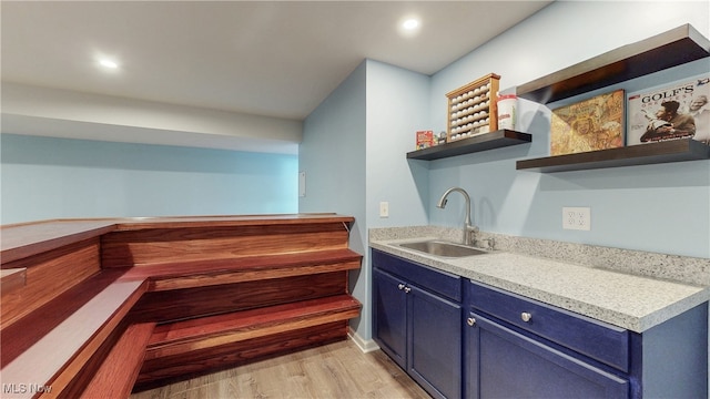 interior space featuring open shelves, a sink, light countertops, blue cabinetry, and light wood-style flooring
