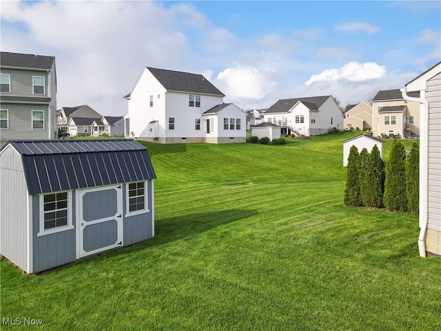 view of yard featuring a residential view, an outbuilding, and a shed
