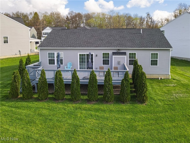 rear view of property with a lawn, roof with shingles, and a deck