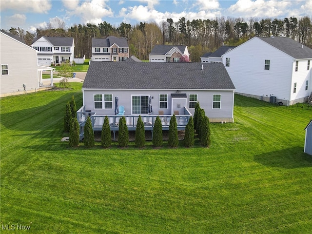 back of house with a lawn, a residential view, roof with shingles, and a deck