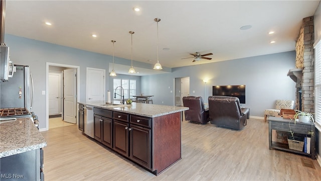 kitchen with a ceiling fan, baseboards, a sink, light wood-style flooring, and stainless steel appliances