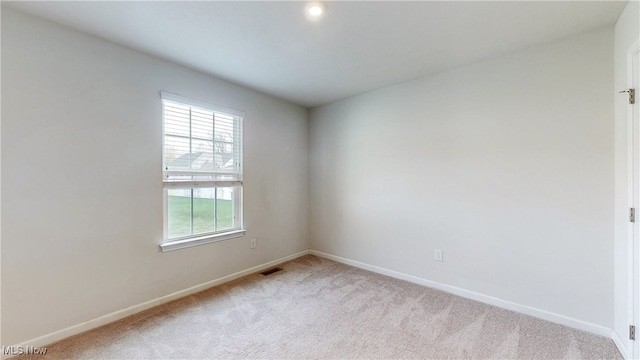 spare room with baseboards, visible vents, and light carpet