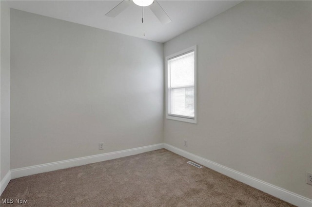 carpeted spare room with baseboards, a ceiling fan, and visible vents