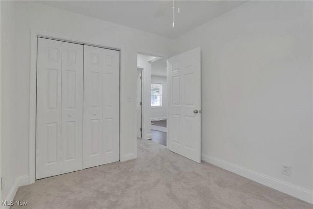 unfurnished bedroom featuring carpet floors, baseboards, and a closet