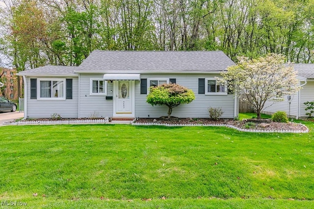 ranch-style home featuring a shingled roof and a front lawn