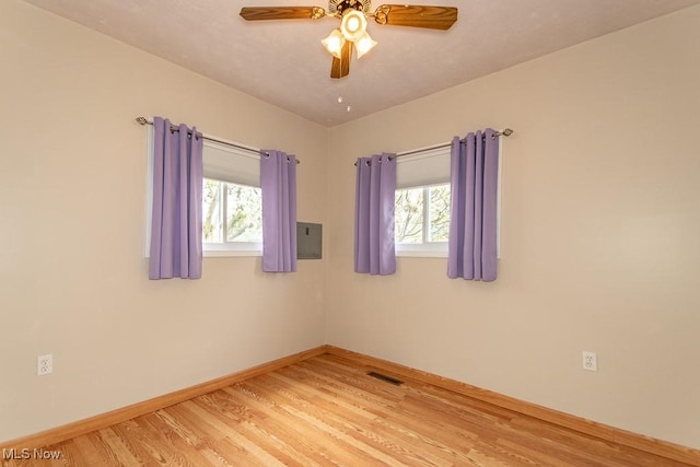 unfurnished room with visible vents, a ceiling fan, light wood finished floors, and baseboards