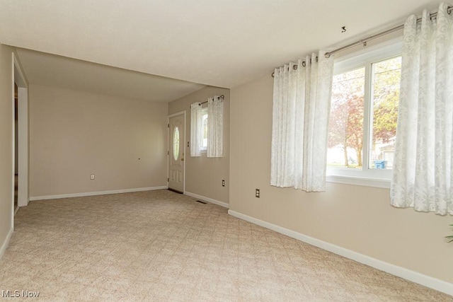 spare room featuring baseboards and light carpet