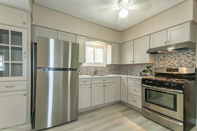 kitchen featuring decorative backsplash, a sink, under cabinet range hood, a ceiling fan, and appliances with stainless steel finishes