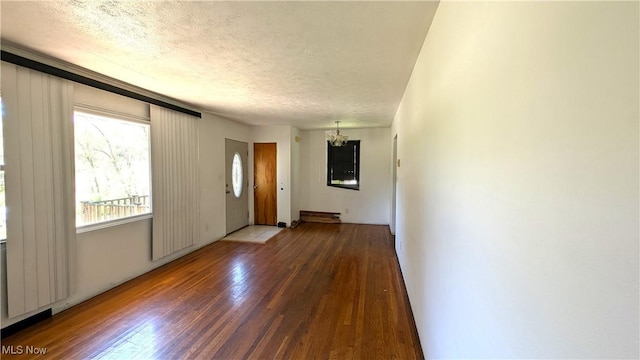 unfurnished living room featuring a textured ceiling, wood finished floors, and a notable chandelier