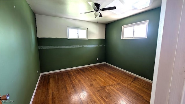 empty room with baseboards, ceiling fan, wood finished floors, and a healthy amount of sunlight