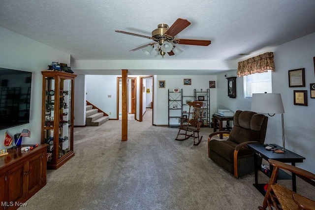 living area with a ceiling fan, stairway, carpet, and a textured ceiling