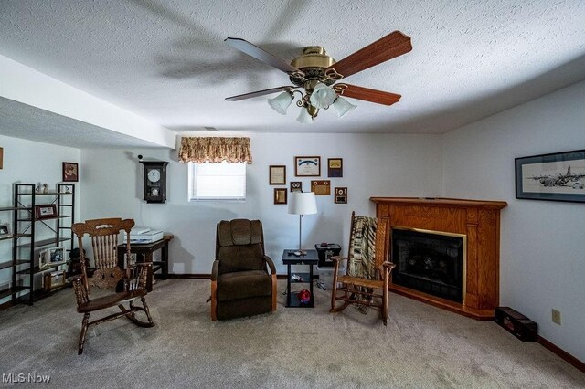 living area featuring a ceiling fan, a textured ceiling, carpet, and a fireplace