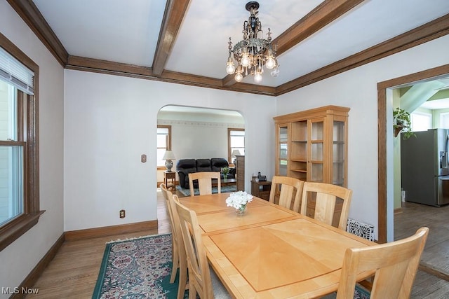 dining space with arched walkways, a notable chandelier, wood finished floors, and a wealth of natural light