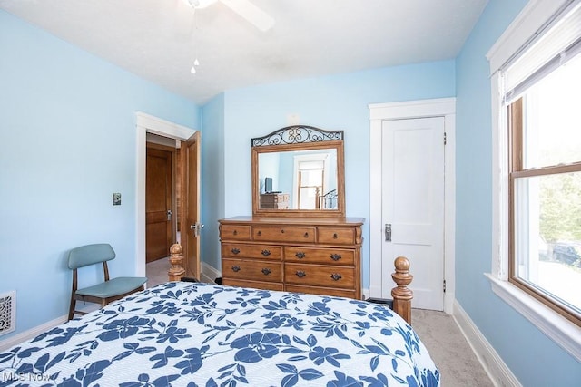bedroom featuring a ceiling fan, baseboards, light colored carpet, and multiple windows