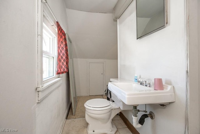 half bath featuring a sink, tile patterned floors, baseboards, and toilet