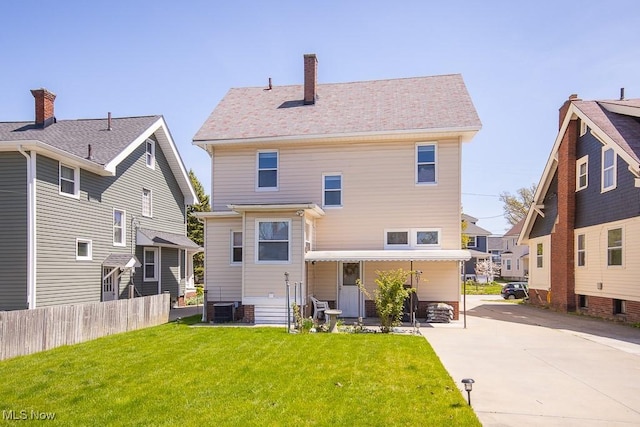 rear view of house with a lawn, fence, and central AC
