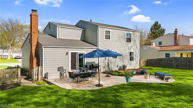 back of property with a chimney, a lawn, fence, a patio, and a shingled roof