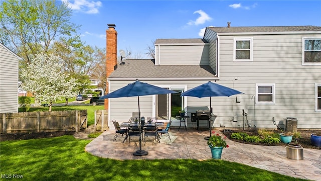 rear view of house featuring a patio, a shingled roof, fence, and a yard