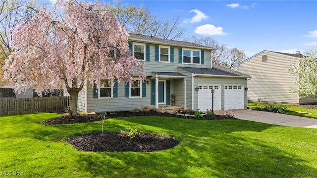 traditional-style home featuring concrete driveway, an attached garage, fence, and a front yard