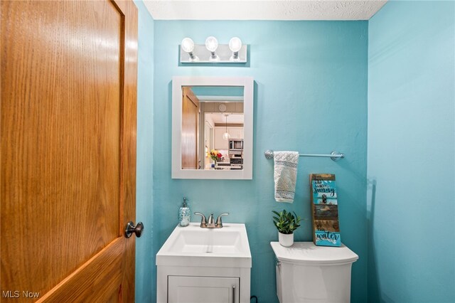 half bathroom with vanity and toilet