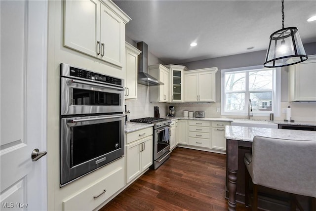 2716 Rocky Ridge Dr, Westlake, OH 44145 - kitchen featuring a sink, wall chimney exhaust hood, dark wood finished floors, light stone countertops, and appliances with stainless steel finishes