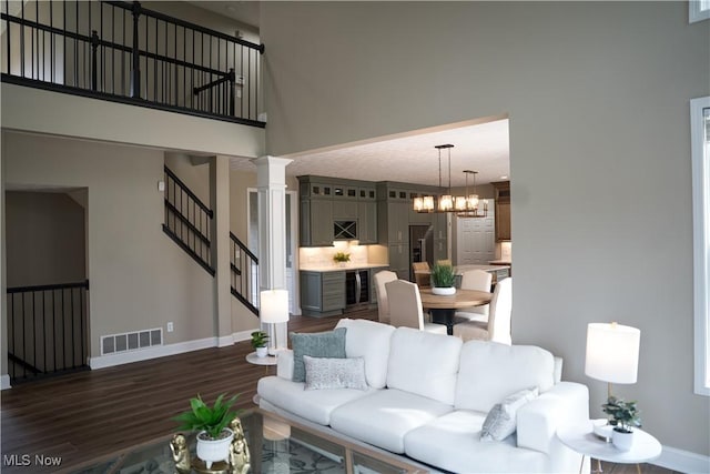 living area featuring visible vents, dark wood finished floors, baseboards, and a chandelier