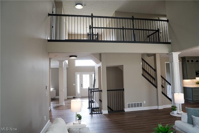 living room featuring a high ceiling, ornate columns, and visible vents
