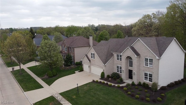 view of front facade featuring roof with shingles, a front lawn, a garage, a chimney, and driveway
