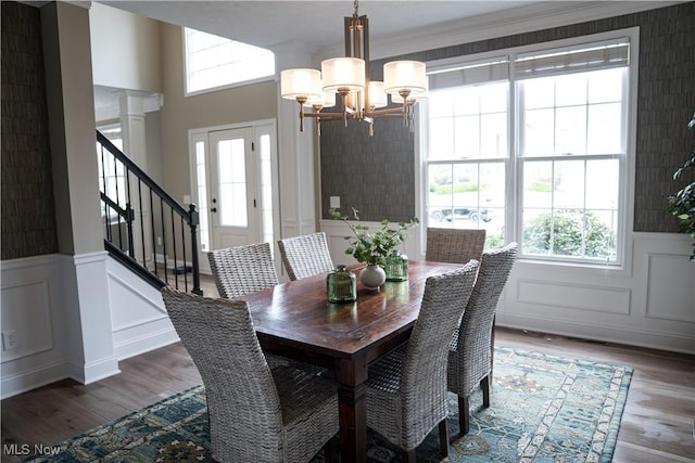 dining space with wood finished floors, a notable chandelier, stairway, and a healthy amount of sunlight
