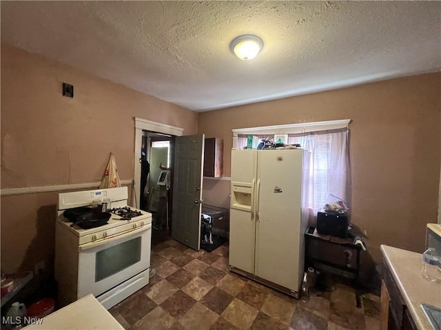 kitchen with dark floors, white appliances, and a textured ceiling