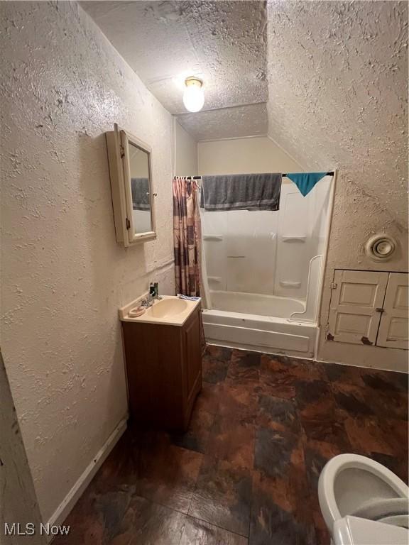 bathroom with vanity, a textured wall, vaulted ceiling, and a textured ceiling