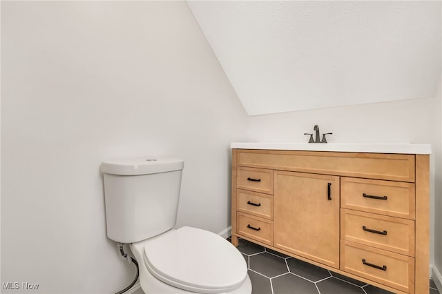 bathroom featuring toilet, tile patterned floors, lofted ceiling, and vanity