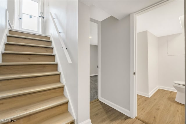 staircase featuring baseboards and wood finished floors