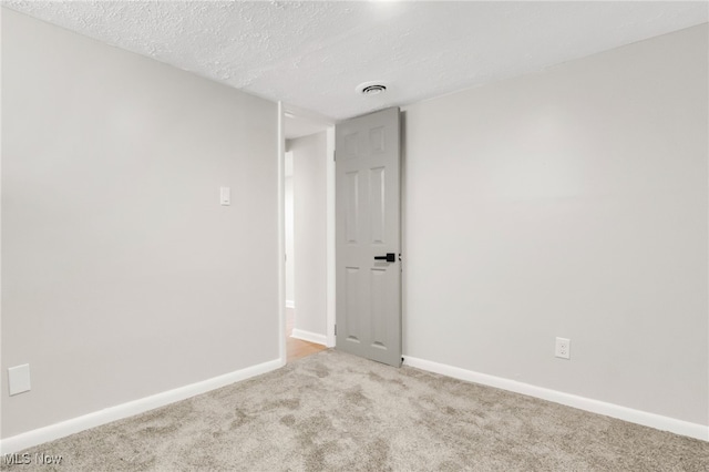 empty room with baseboards, a textured ceiling, and carpet