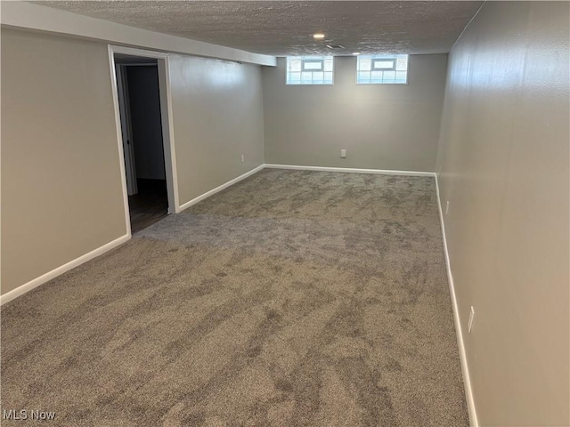 basement with baseboards, carpet flooring, and a textured ceiling