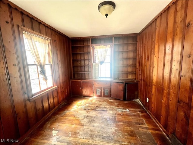 empty room with wooden walls, hardwood / wood-style flooring, and built in shelves