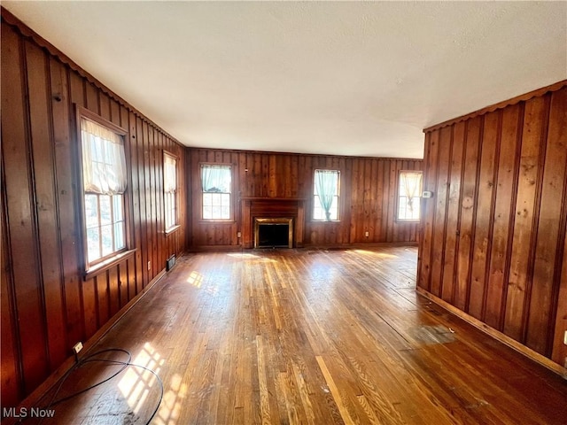 unfurnished living room featuring wood walls, hardwood / wood-style flooring, and a fireplace