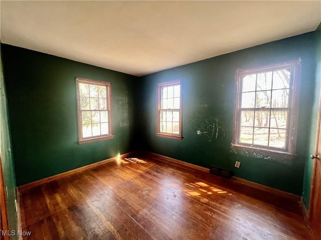 spare room featuring baseboards, hardwood / wood-style flooring, and visible vents