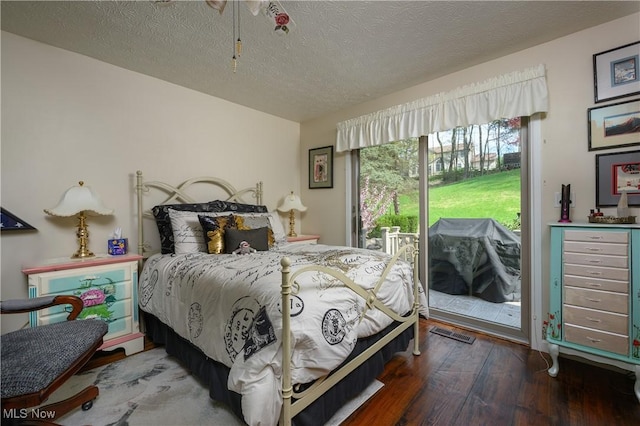 bedroom with access to outside, a textured ceiling, wood finished floors, and visible vents