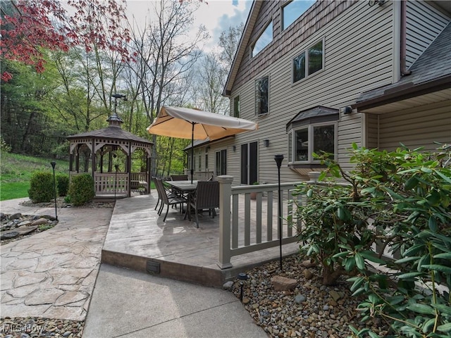 wooden terrace with outdoor dining space, a gazebo, and a patio