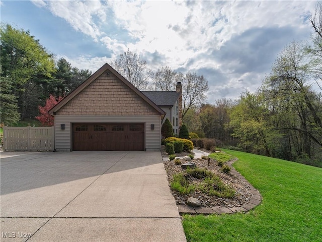 view of side of home with a yard, an attached garage, driveway, and a chimney