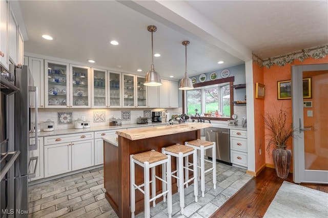kitchen featuring dishwasher, white cabinets, a breakfast bar, and tasteful backsplash