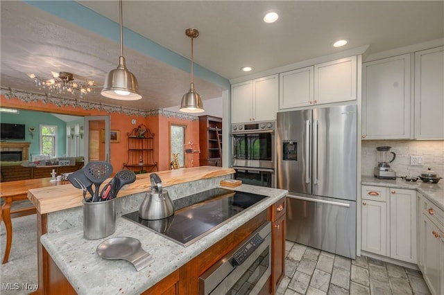 kitchen featuring white cabinets, stainless steel appliances, decorative light fixtures, and backsplash