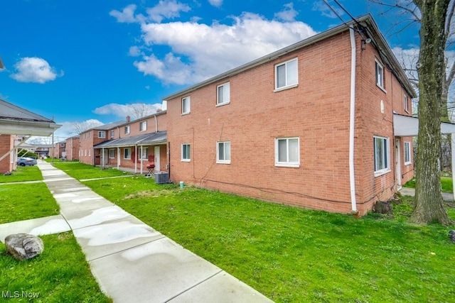 exterior space with a lawn, brick siding, and central air condition unit